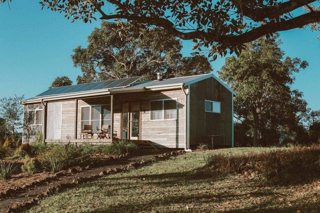 Wooden House With Solar Panels Near Green Trees